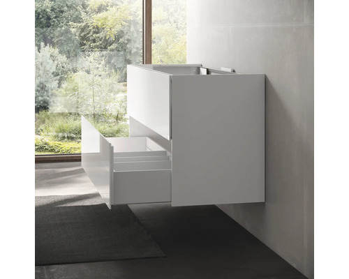 Meuble sous-lavabo blanc avec tiroirs ouverts monté sur un mur de salle de bains