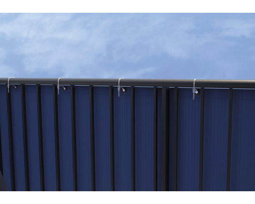 Vue détaillée d''un écran de confidentialité fixé à une balustrade sur un ciel bleu.