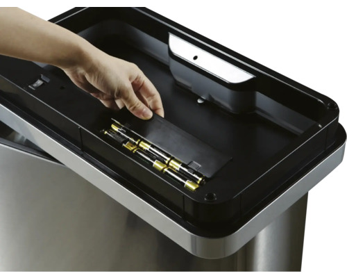 Mülleimer mit Batteriefach und Hand, die eine Batterie einlegt