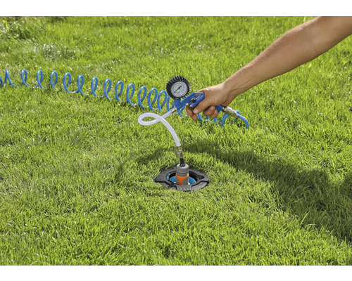 Eine im Rasen installierte Sprinkleranlage wird mit einem Druckluftprüfer überprüft.