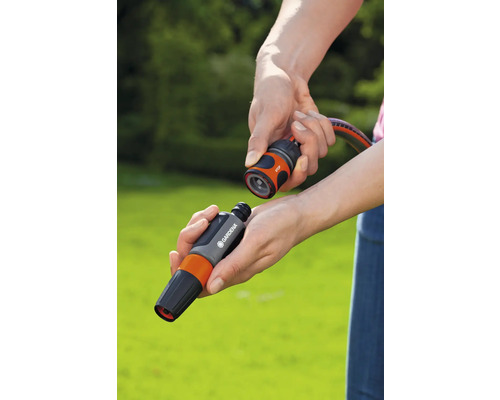 Des mains raccordent un raccord de tuyau Gardena avec un arrêt d''eau