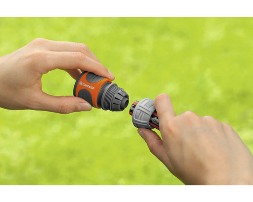 Deux mains connectent un raccord de tuyau Gardena.