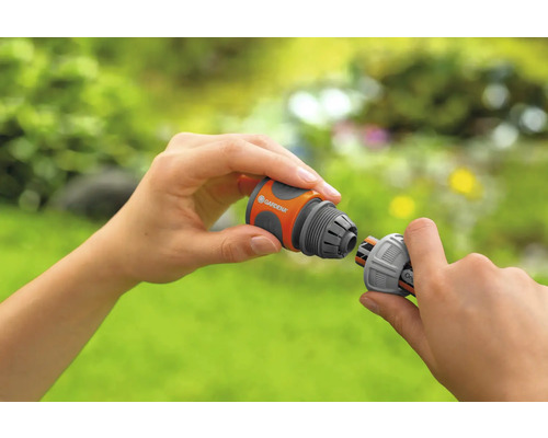 Deux mains connectent deux raccords de tuyau Gardena.