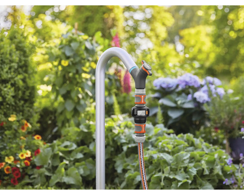 Gartenszene mit Wasserhahn, Schlauch und digitalem Wasserzähler im Garten
