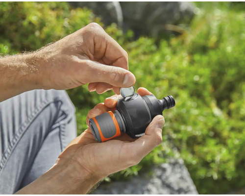 Eine Person setzt eine Münze in eine Gartenwasserzeitschaltuhr ein.