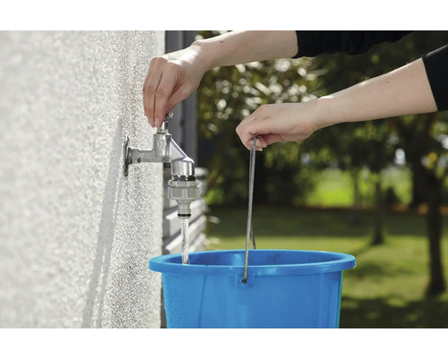 Wasserhahn wird aufgedreht, um einen Eimer zu füllen