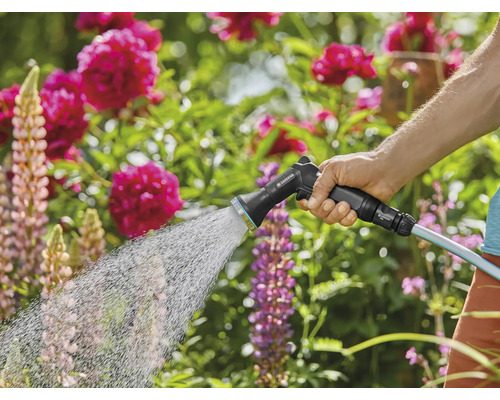 Une personne arrose un jardin avec un pistolet d''arrosage.
