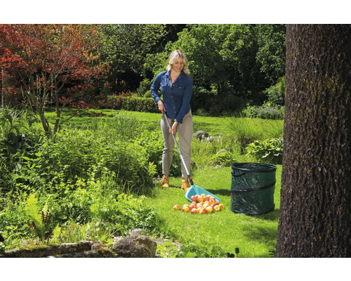 Femme ramassant des pommes avec un cueille-fruits dans un jardin