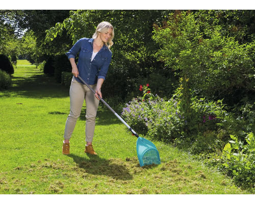 Une femme travaille avec un collecteur de feuilles dans le jardin.