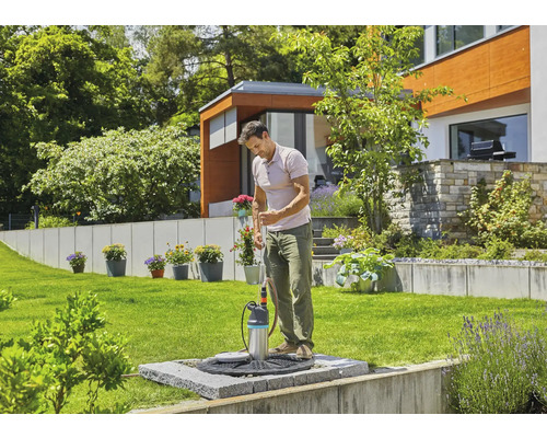 Ein Mann benutzt eine Tauchpumpe im Garten für die Bewässerung.