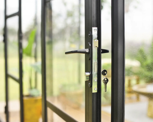 Gros plan d''une porte vitrée noire avec poignée de porte, serrure et clés.