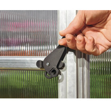 Un homme actionne un loquet noir sur une fenêtre de serre