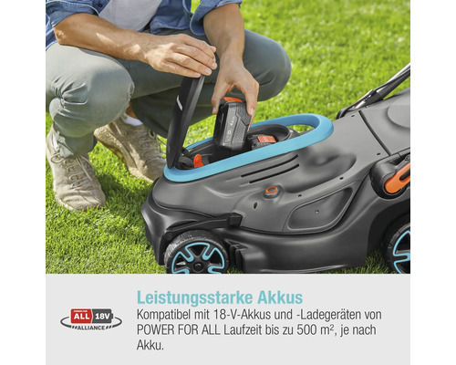 Eine Person setzt einen Akku in einen Rasenmäher auf einer Rasenfläche.