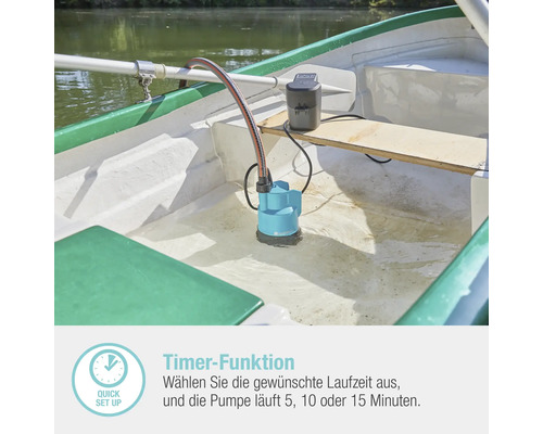 Eine Tauchpumpe mit Schlauch und Akku steht im Wasser in einem Boot.