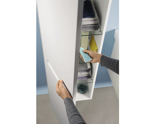 Une personne ouvre une armoire de salle de bains avec des étagères pour ranger les serviettes et les articles de toilette.