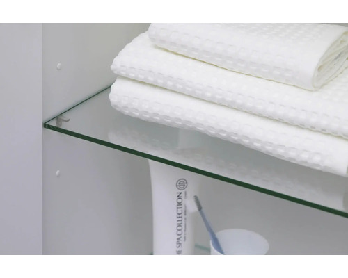 Étagère en verre dans une armoire de salle de bains avec des serviettes et des produits de soin