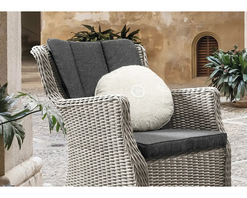 Geflochtener Sessel mit Kissen und runder Zierdeko für den Garten