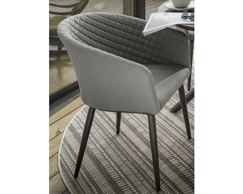 Fauteuil gris avec motif losanges et pieds foncés sur un tapis à motifs