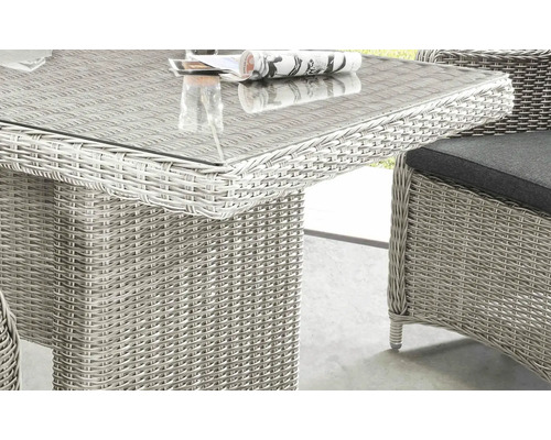 Vue détaillée d''une table de jardin avec plateau en verre et surface en rotin, ainsi que d''une chaise avec coussin