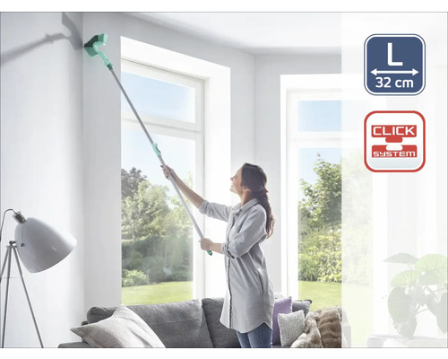 Frau reinigt Ecke mit Deckenbürste am Teleskopstiel im Wohnzimmer