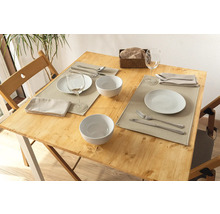 Gedeckter Holztisch mit Tellern, Schüsseln, Besteck, Servietten und Tischsets für zwei Personen