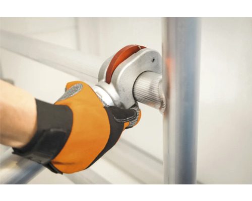 Eine Person befestigt mit einer Rohrverbindung eine Gerüststange