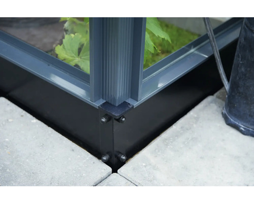 Detailansicht einer Gewächshauskonstruktion mit Aluminiumrahmen und Fundament auf Steinplatten.
