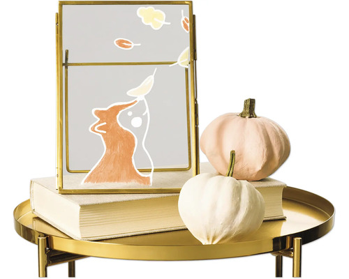 Dekorative Herbstszene mit Kürbissen und Bilderrahmen auf einem goldenen Tisch