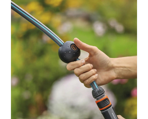 Une main tient un tuyau d''arrosage avec fonction d''arrêt d''eau