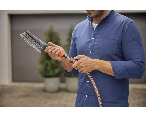 Homme raccordant une brosse à un tuyau d''arrosage