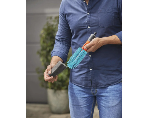 Un homme tient une brosse de nettoyage et une éponge pour l''arrosage du jardin.