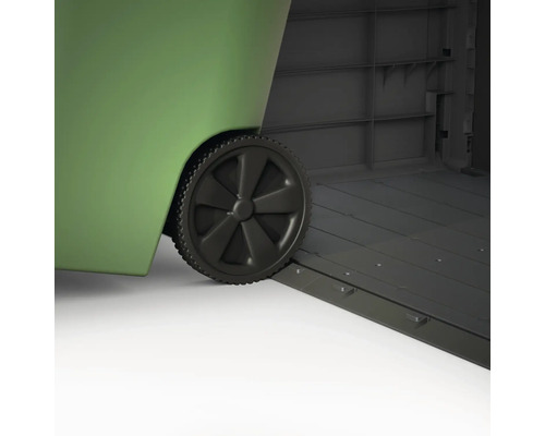 Detailaufnahme eines grünen Mülltonnencontainers mit Rädern, der in einem grauen Gerätehaus steht