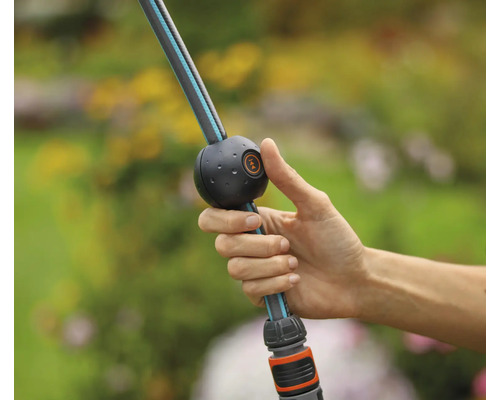 Eine Hand bedient einen flexiblen Gartenschlauch mit einstellbarem Wasserdurchfluss