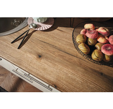 Plan de travail de cuisine avec évier, corbeille de fruits, assiettes et couverts.