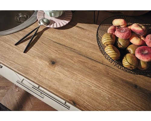 Plan de travail de cuisine avec évier, corbeille de fruits, assiettes et couverts.