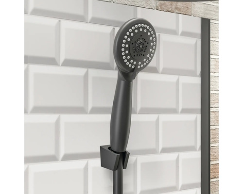 Handbrause im Badezimmer mit weißen Fliesen im Hintergrund.