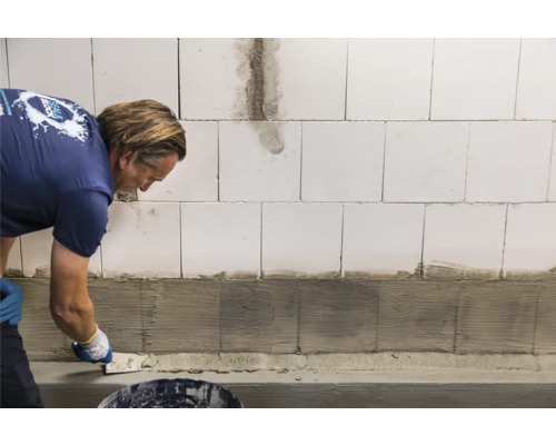 Handwerker trägt Putz auf Wand auf