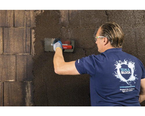 Mann trägt Dichtschlämme mit einer Glättkelle auf eine Wand auf