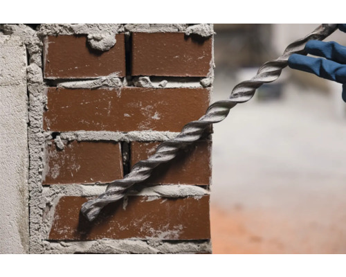 Wand aus Ziegelsteinen mit spiralförmigem Bohrer