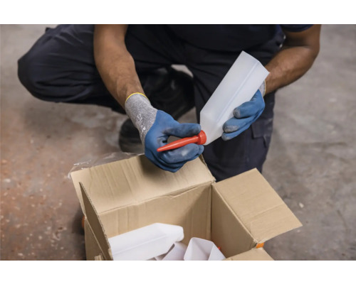 Eine Person setzt einen roten Ausgießer auf eine weiße Kunststoffflasche über einem Karton.