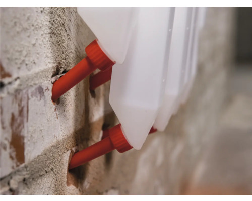 Mehrere Injektionskanister zur Mauertrockenlegung sind in einer Ziegelwand befestigt.