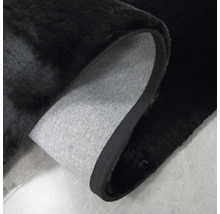 Tapis noir avec coin retroussé montrant le dos en tissu