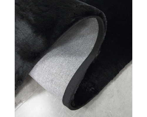 Tapis noir avec coin retroussé montrant le dos en tissu