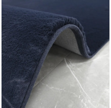 Vue détaillée d''un tapis bleu foncé avec des poils sur un fond gris