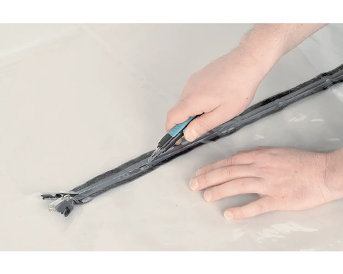 Zwei Hände schneiden mit einem Cutter eine Dichtung