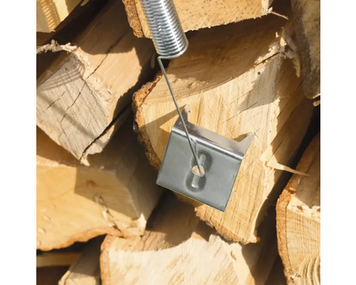 Ressort de fendeur de bûches devant une pile de bois de chauffage