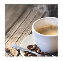 Dekobild mit Tasse Kaffee, Kaffeebohnen und Löffel auf Holztisch