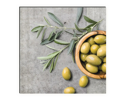 Stillleben mit Oliven in einer Holzschale und Olivenzweig auf Betonhintergrund