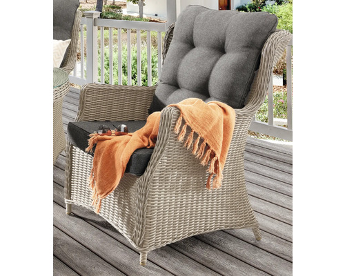 Fauteuil en rotin avec coussins d''assise et de dossier et une couverture sur une terrasse