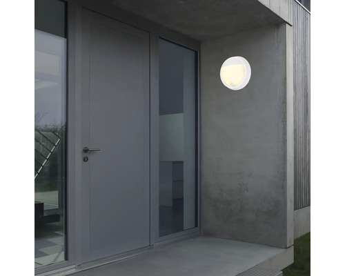 Luminaire extérieur rond blanc sur un mur de maison à côté d''une porte